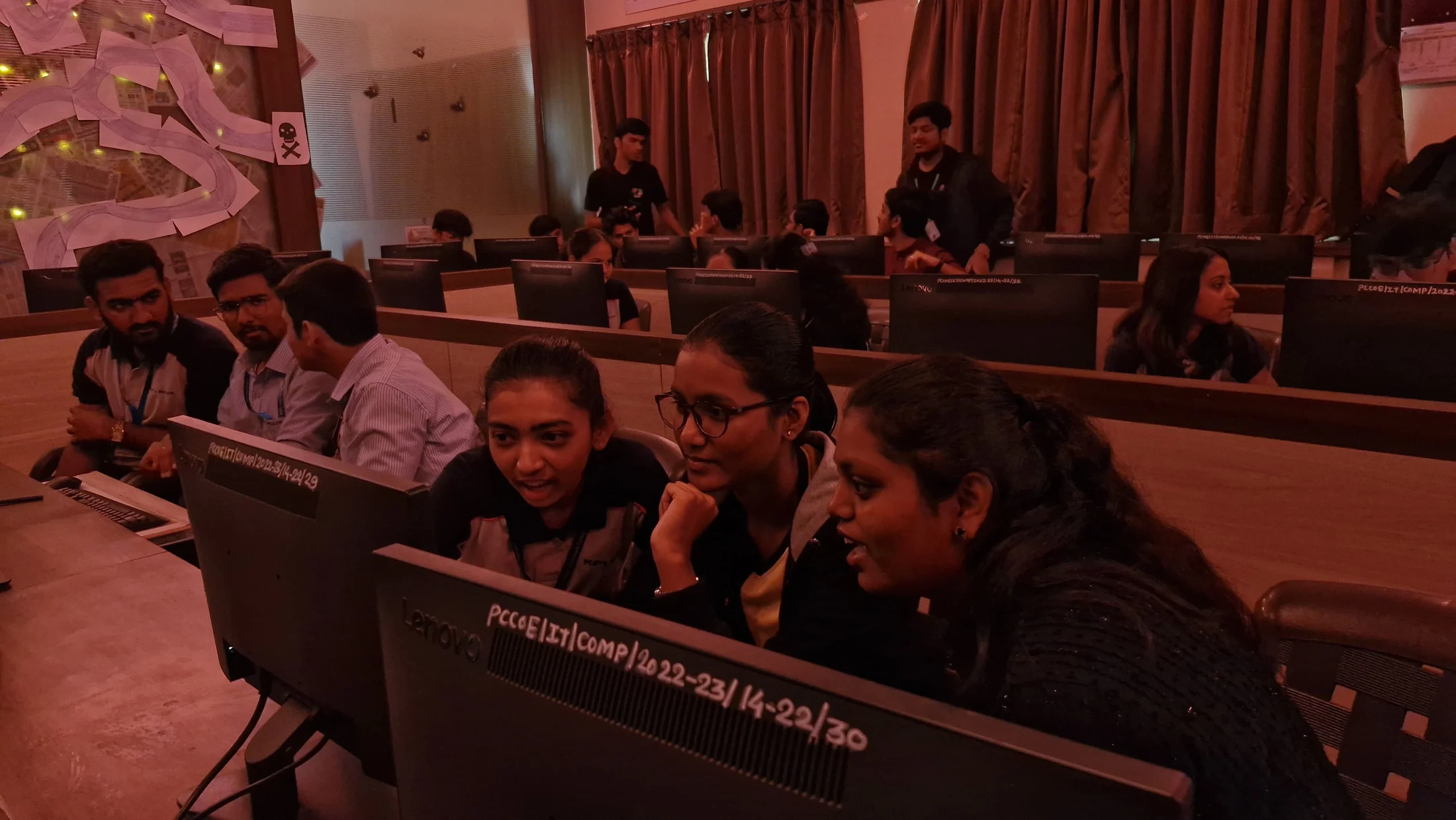 Participants focused on computer screens in a dimly lit event room