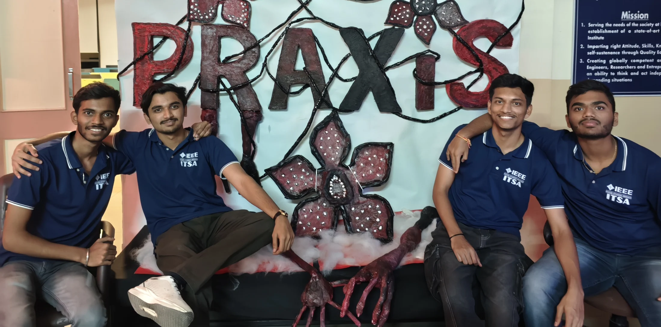 Four students posing beside a handmade Praxis display