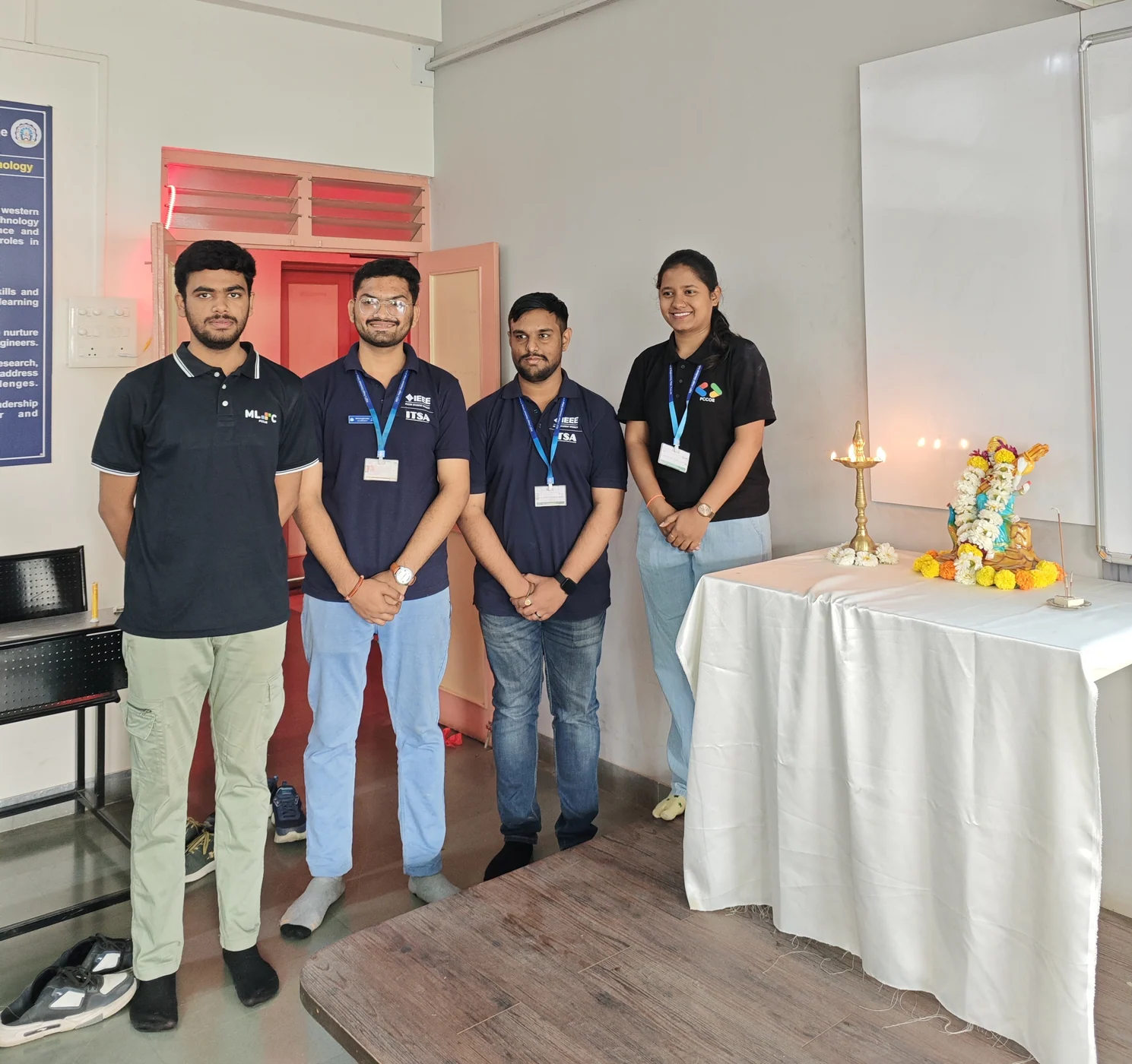 Four students in dark shirts standing together beside a decorated table