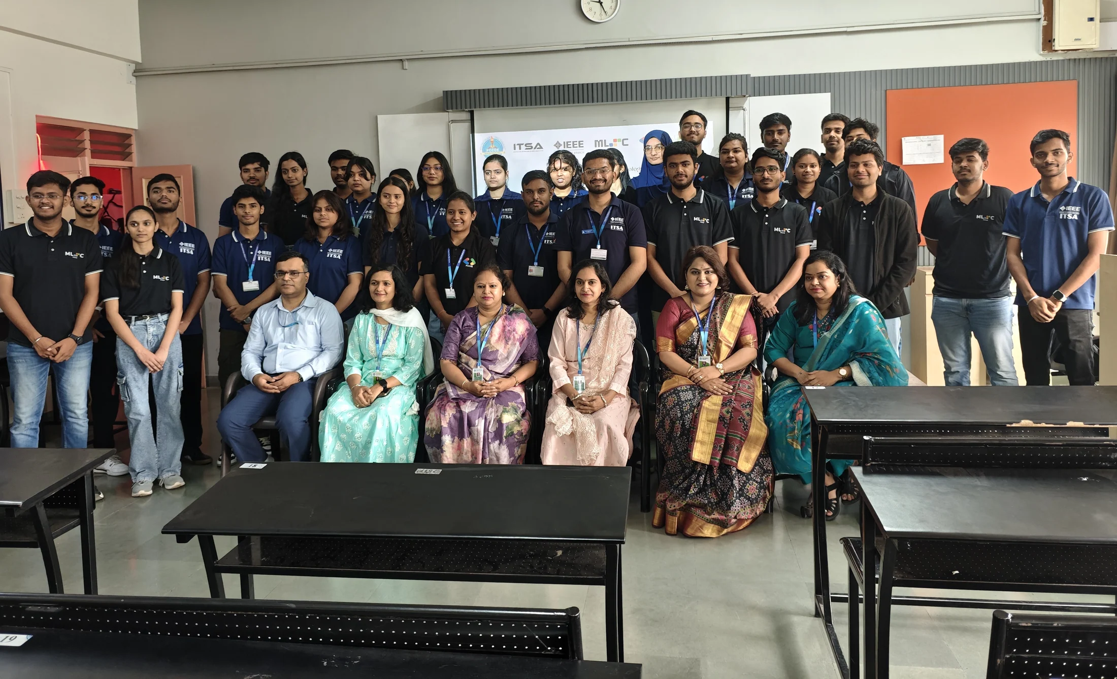 Students and guests gathered for a group photograph at the front of a classroom